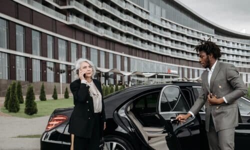 Chauffeur opening the door for a client in business attire.