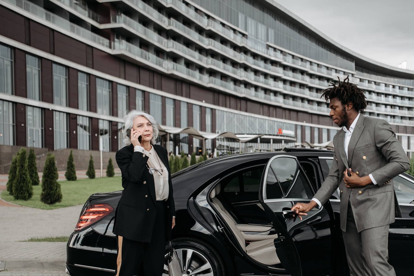 Chauffeur opening the door for a client in business attire.